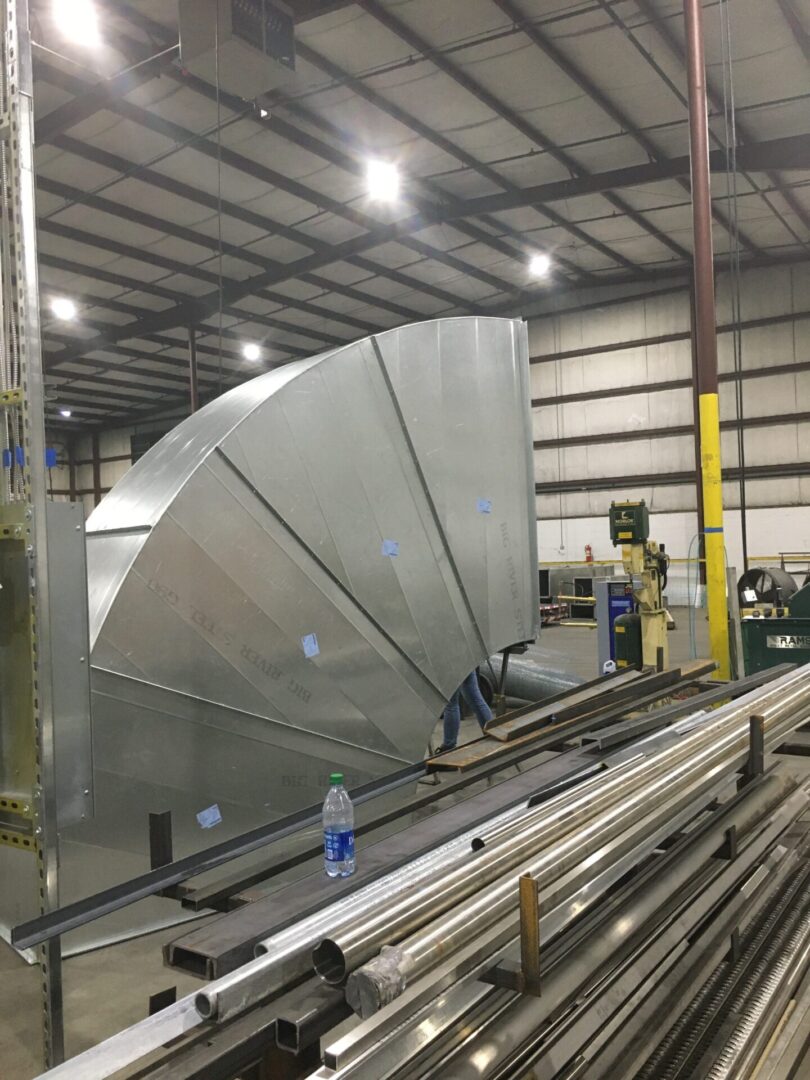 A large metal object in a warehouse with workers.