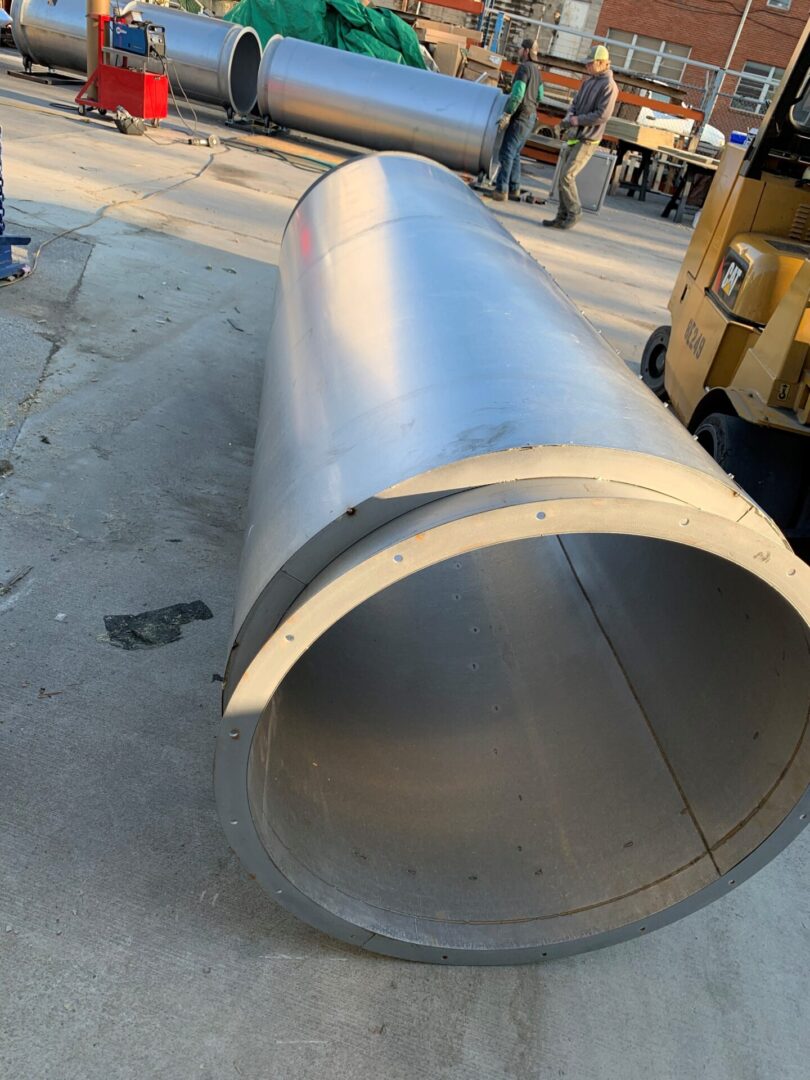 A large metal tube sitting on top of concrete.
