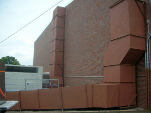 A building with a large brick wall and a white fence.
