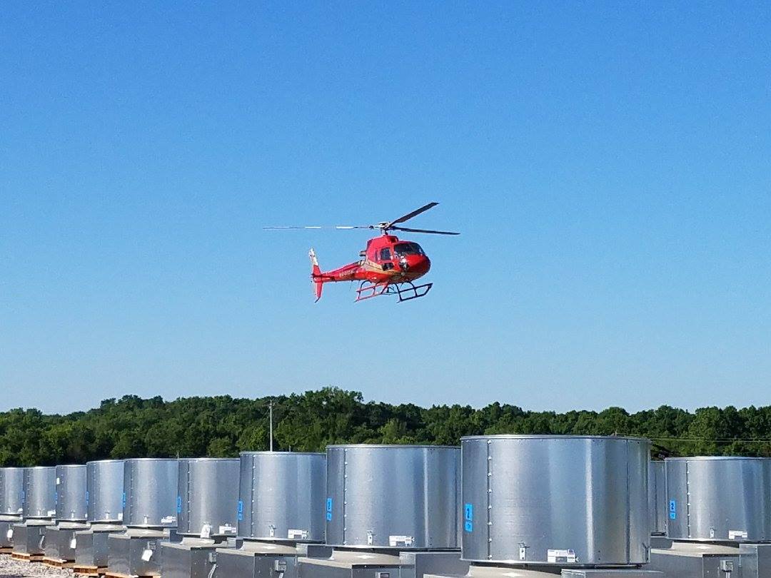 A helicopter flying over some metal barrels
