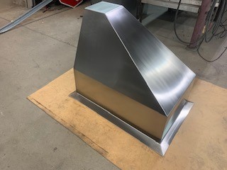 A stainless steel hood sitting on top of a wooden floor.